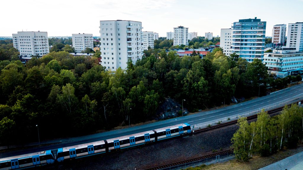 Vy över Högdalen med tunnelbana och grönområde i förgrunden. Foto